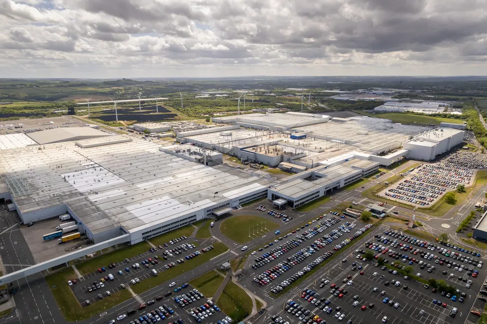 Luchtfoto van een grote autofabriek met vol parkeerterrein.