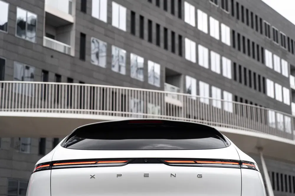 Arrière de la voiture XPeng blanche devant un immeuble moderne.