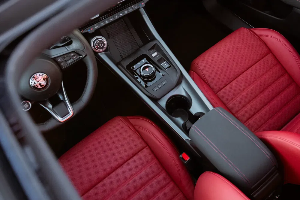 Intérieur de l'Alfa Romeo, sièges rouges, console centrale élégante avec sélecteur rotatif.