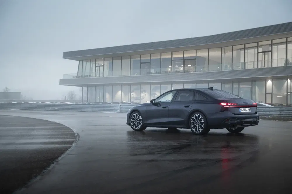 Audi RS e-tron GT op natte baan voor modern gebouw.