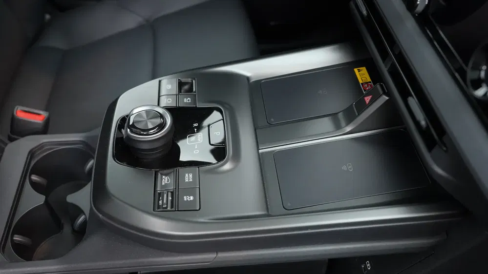 Console centrale de voiture avec chargeurs sans fil et contrôleur, compartiments pour boissons.