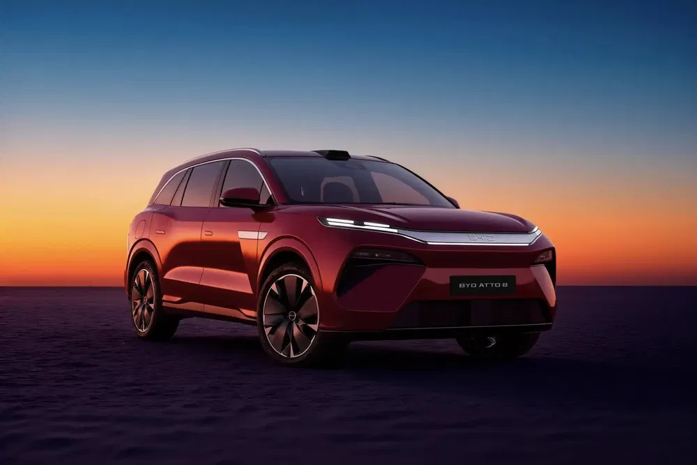 SUV BYD Atto 3 rouge devant un coucher de soleil spectaculaire.