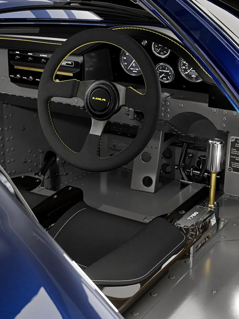 Interieur van een Lola raceauto met een sportstuur en aluminium dashboard.