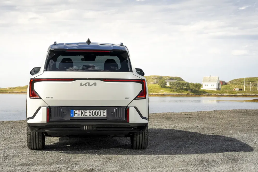 Vue arrière du Kia EV5 blanc, stationné près d'un lac sous un ciel dégagé.