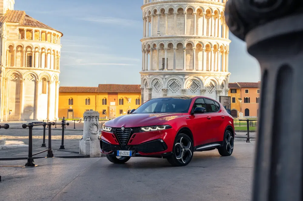 Alfa Romeo SUV rouge devant la Tour de Pise, mettant en valeur un design élégant.