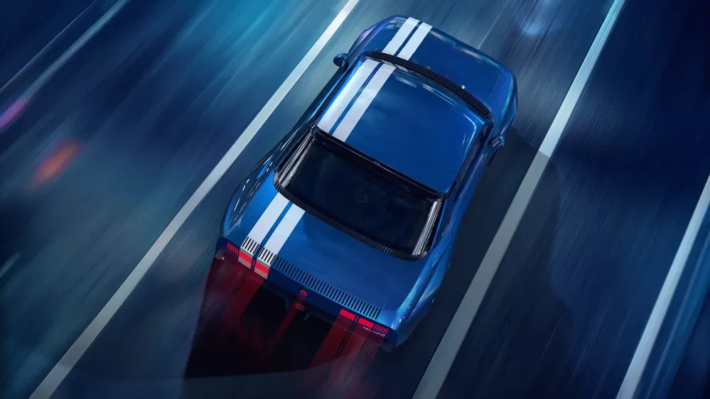 Voiture bleue sportive avec bandes blanches roulant rapidement sur autoroute nocturne.