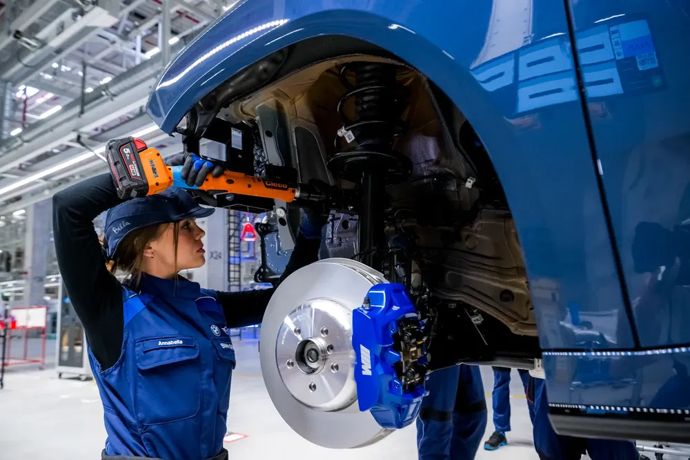 Technicus monte ophanging van elektrische auto in moderne Volkswagen-fabriek.