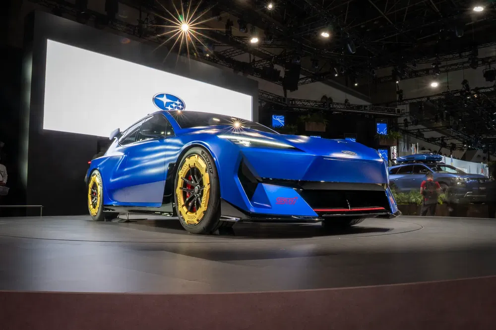 Blauwe Subaru conceptauto met gele velgen op een podium tijdens een autosalon.