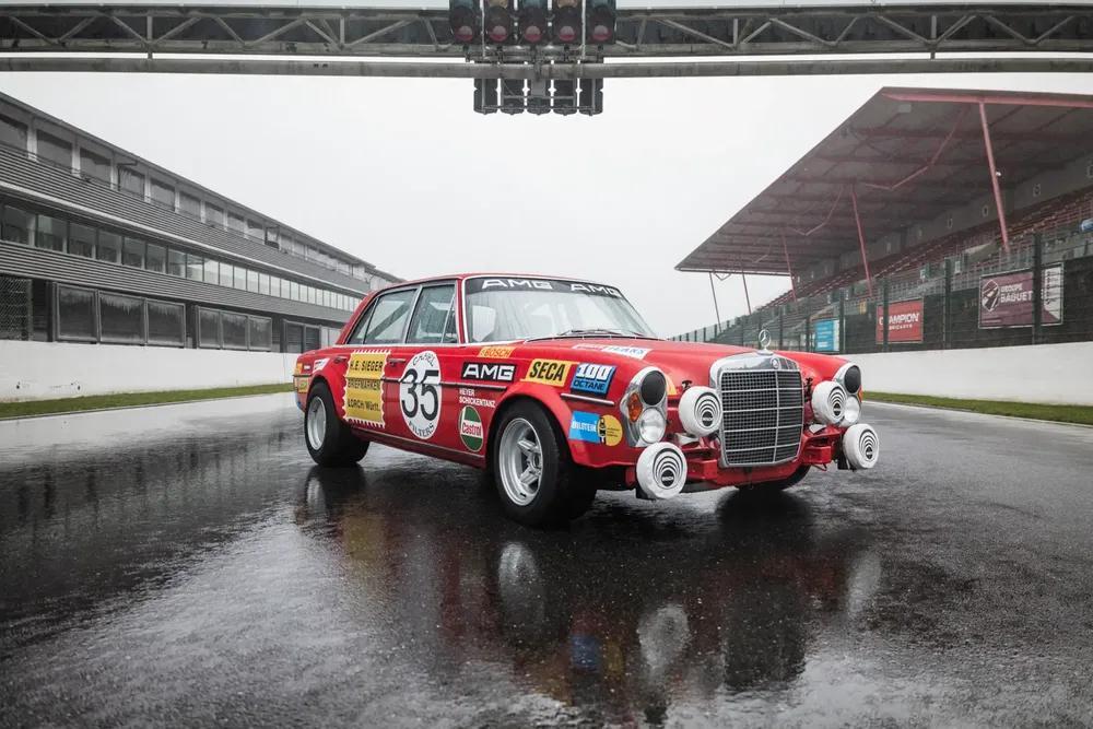 Mercedes-Benz 300 SEL AMG de course sur piste mouillée, voiture classique rouge, années 1970.