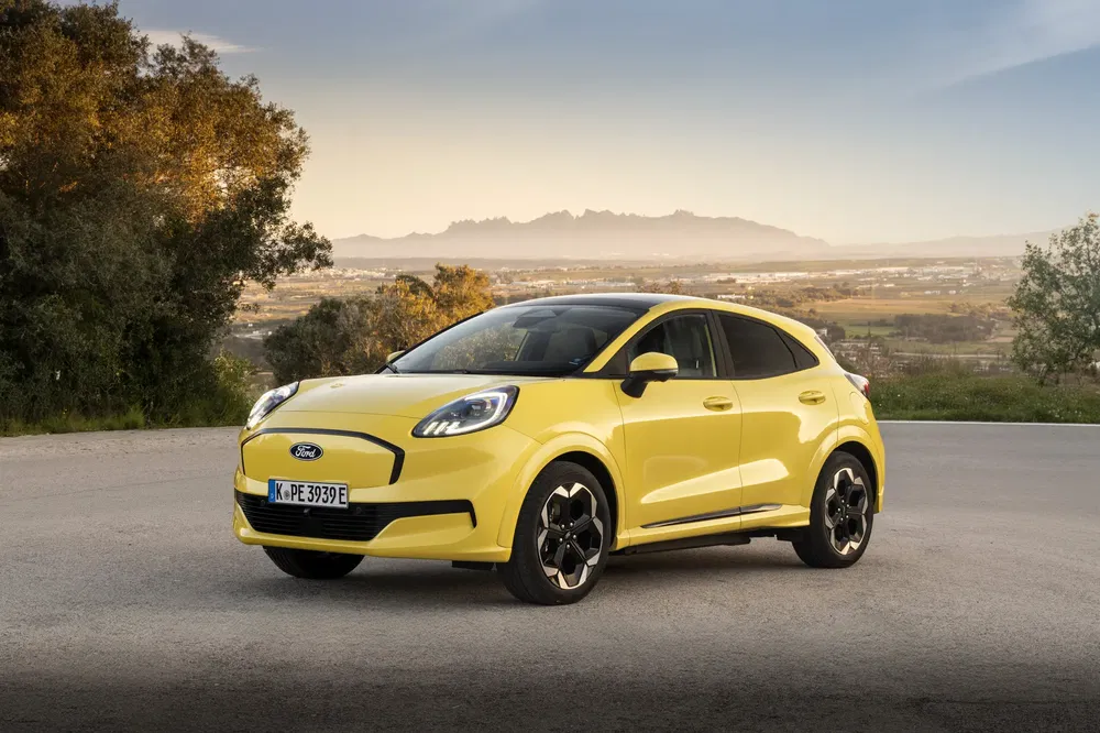 Ford Puma jaune sur route, paysages montagneux en arrière-plan au crépuscule.