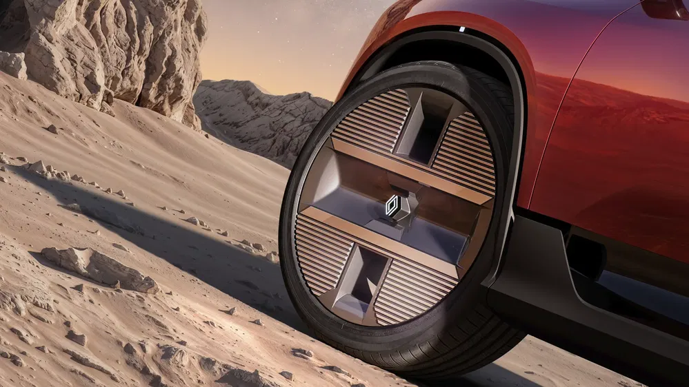 Roue de voiture Renault en gros plan sur terrain désertique, design futuriste avec jantes métalliques.