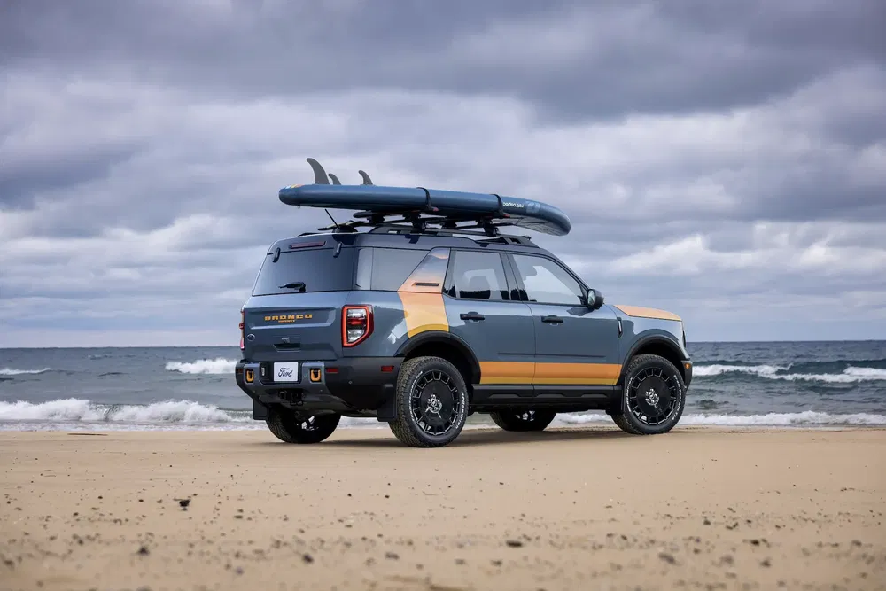 Ford Bronco Sport sur la plage avec planche de surf sur le toit.