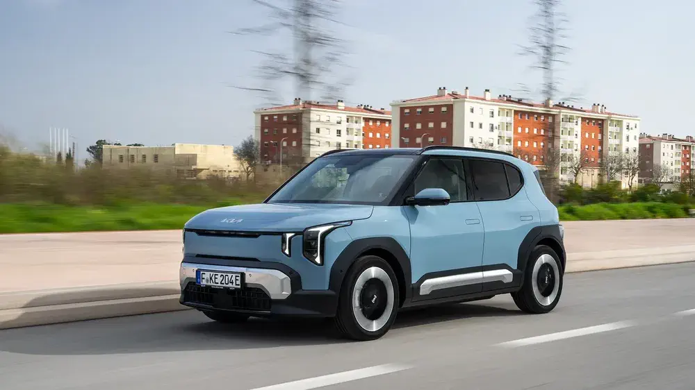 Le SUV électrique Kia EV4 bleu roulant en milieu urbain devant des immeubles résidentiels.
