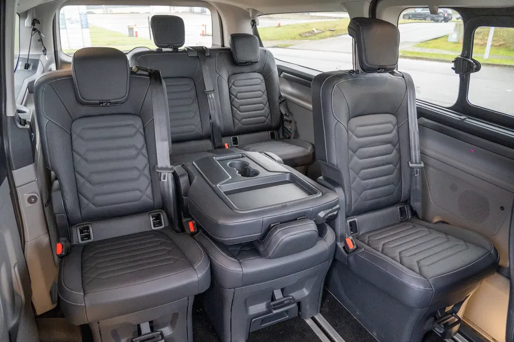 Intérieur Volkswagen Multivan avec sièges en cuir noir et console centrale rabattable.