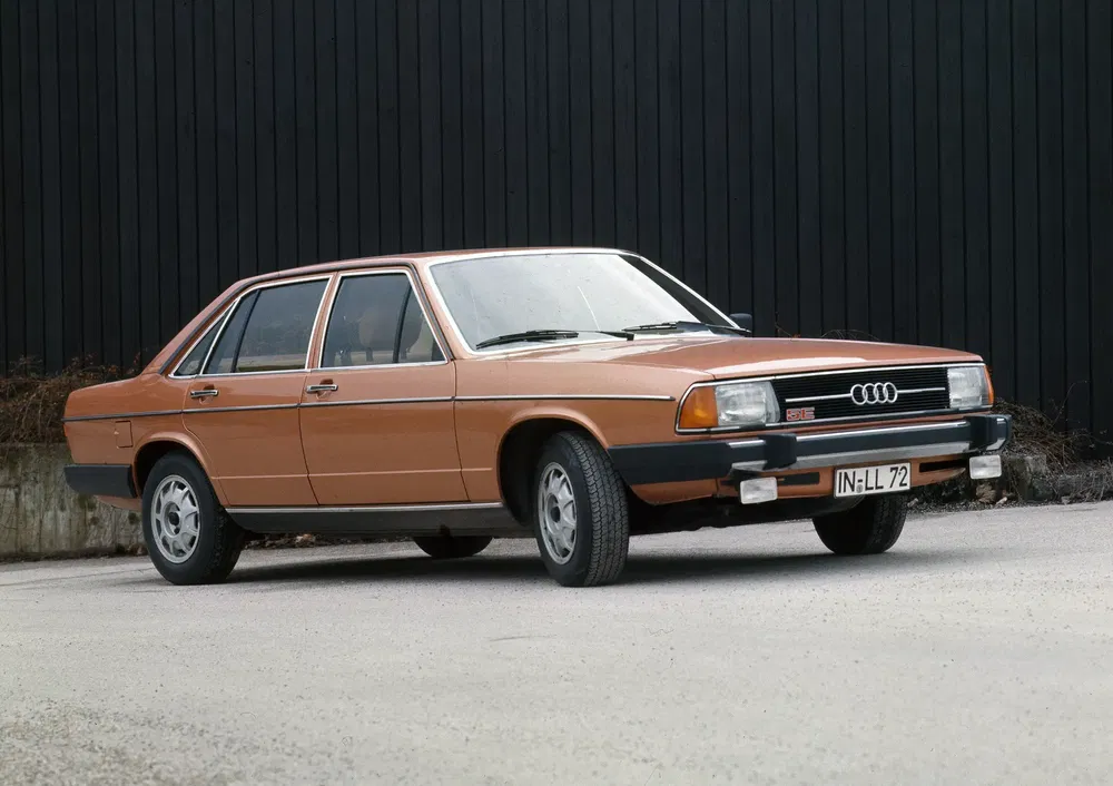 Audi 200 marron des années 1980 garée sur fond noir, design classique et rétro.