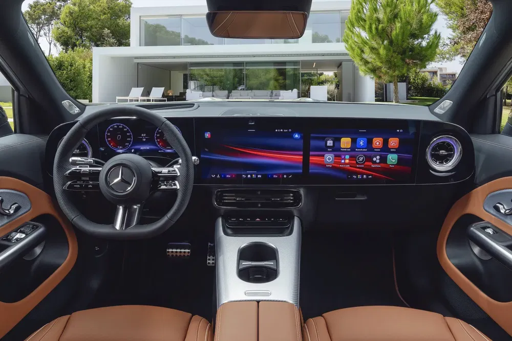 Intérieur moderne d'une Mercedes, tableau de bord numérique devant une maison contemporaine.