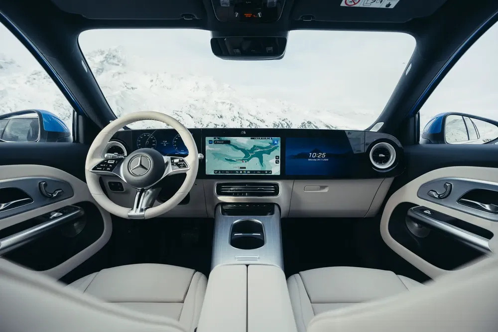 Intérieur de voiture Mercedes moderne avec tableau de bord numérique sur fond de montagnes enneigées.