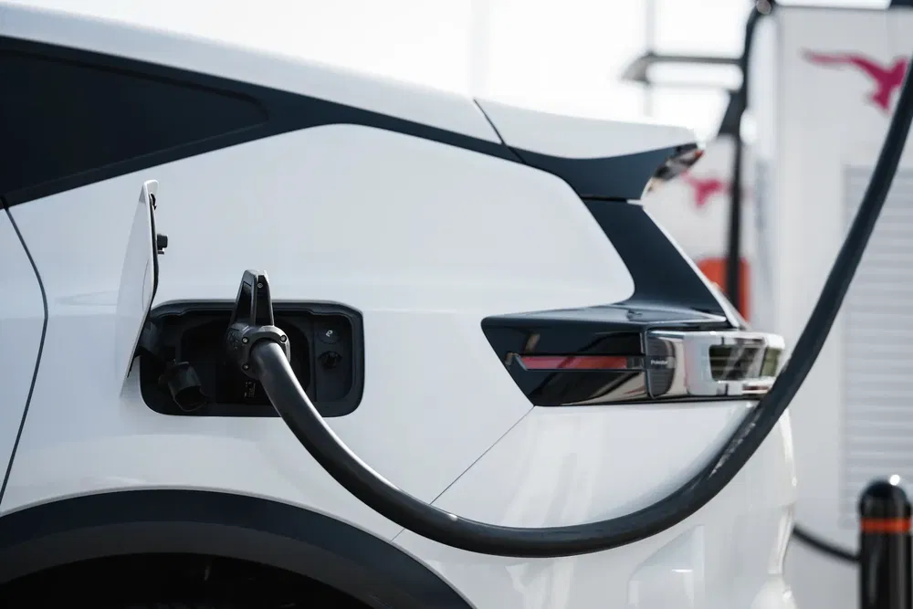 Véhicule électrique blanc en charge, connecteur inséré à l'arrière, design moderne et épuré.