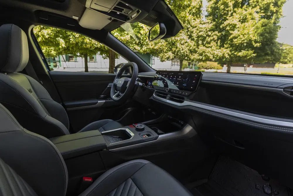 Intérieur moderne de voiture électrique Kia EV5, écran tactile central, sièges en cuir noir.