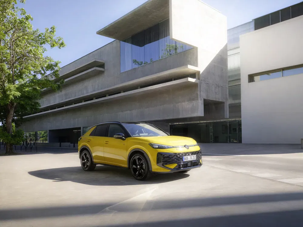 Gele Volkswagen ID.5 voor een modern betonnen gebouw met grote ramen.