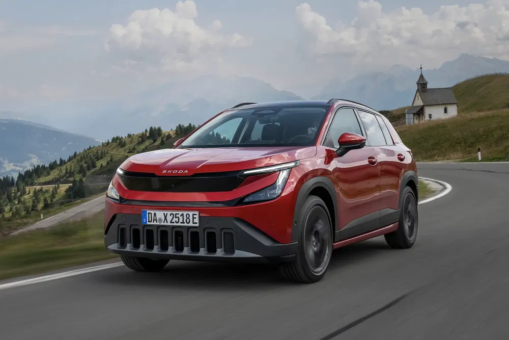 {"fr":"SUV Skoda rouge moderne sur route de campagne pittoresque avec montagne en arrière-plan.","nl":"Moderne rode Skoda SUV op schilderachtige landweg met bergen op de achtergrond."}