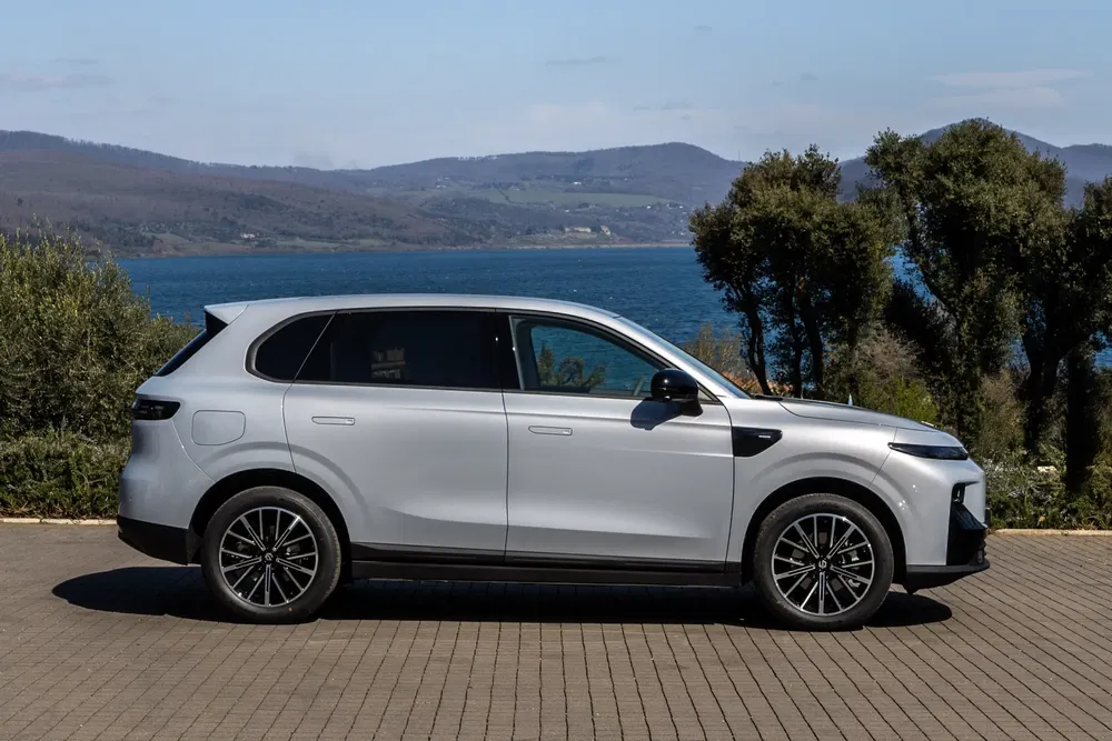 Witte elektrische SUV, kustlandschap op de achtergrond, geplaveide weg.