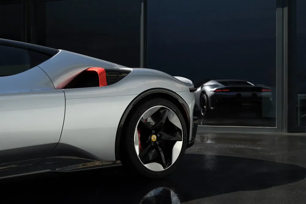 Zilveren Ferrari SF90 Stradale met close-up wiel, weerspiegeling in moderne raam.