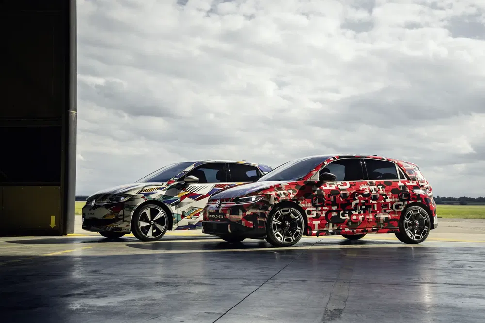 Deux prototypes de Volkswagen ID.2 camouflés avec des motifs colorés sur une piste aérienne.