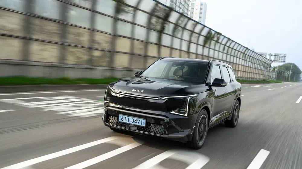 SUV Kia électrique noir roulant sur une route urbaine.