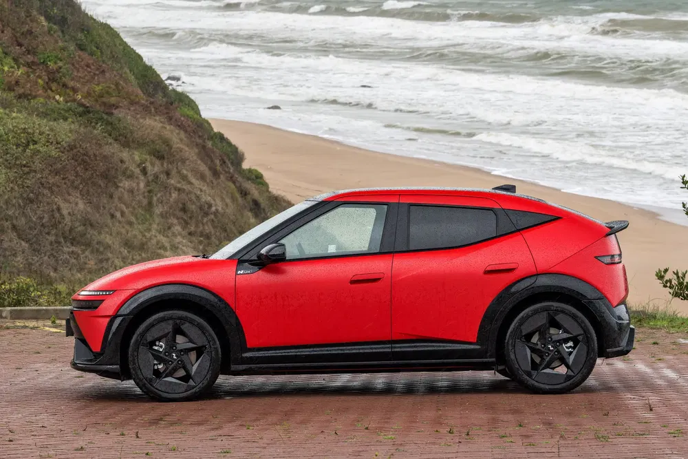 Rode elektrische crossover bij oceaan, modern en sportief ontwerp.
