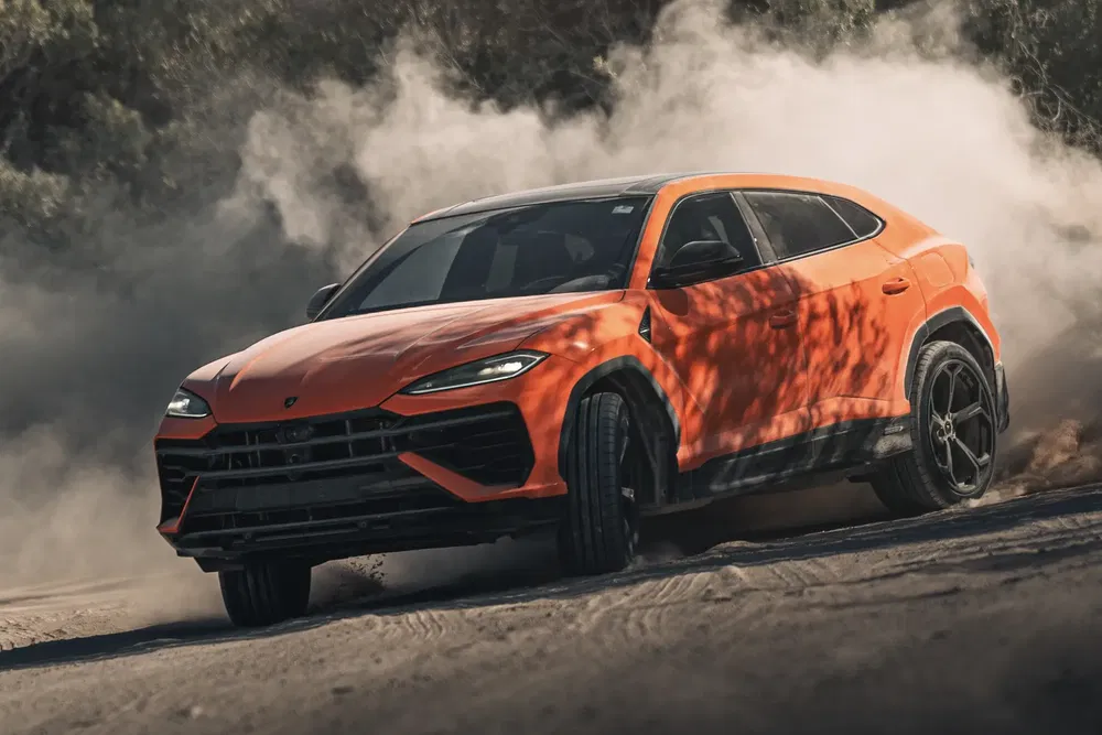 {"fr":"Lamborghini Urus 2023 orange en drift sur route poussiéreuse, entouré de nuages de poussière.","nl":"Oranje Lamborghini Urus 2023 driftend op stoffige weg, omringd door stofwolken."}