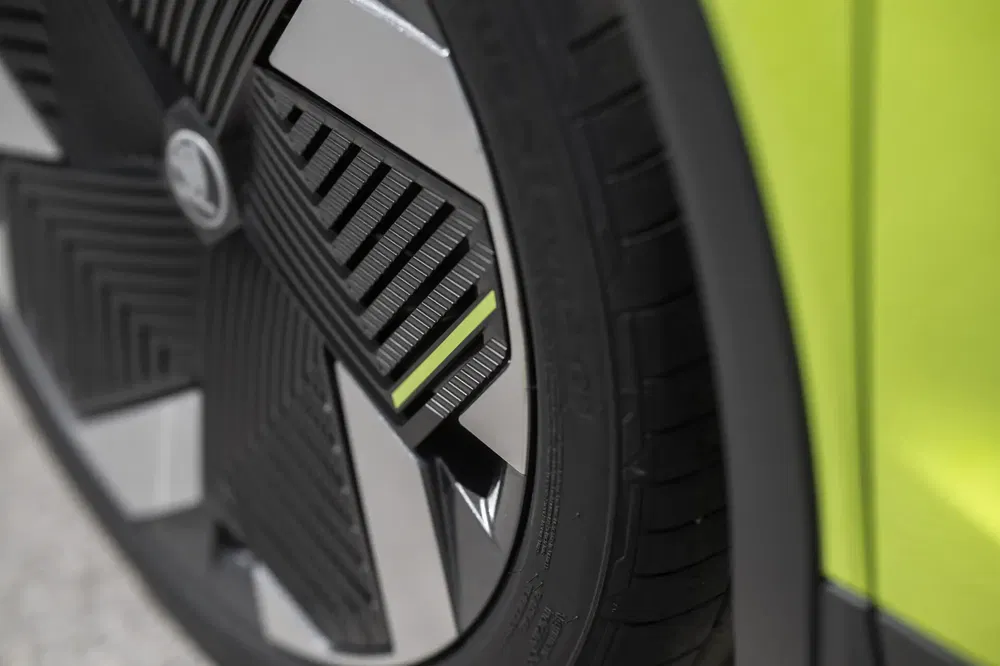 Close-up van geometrisch ontworpen velg van een limegroene Skoda.