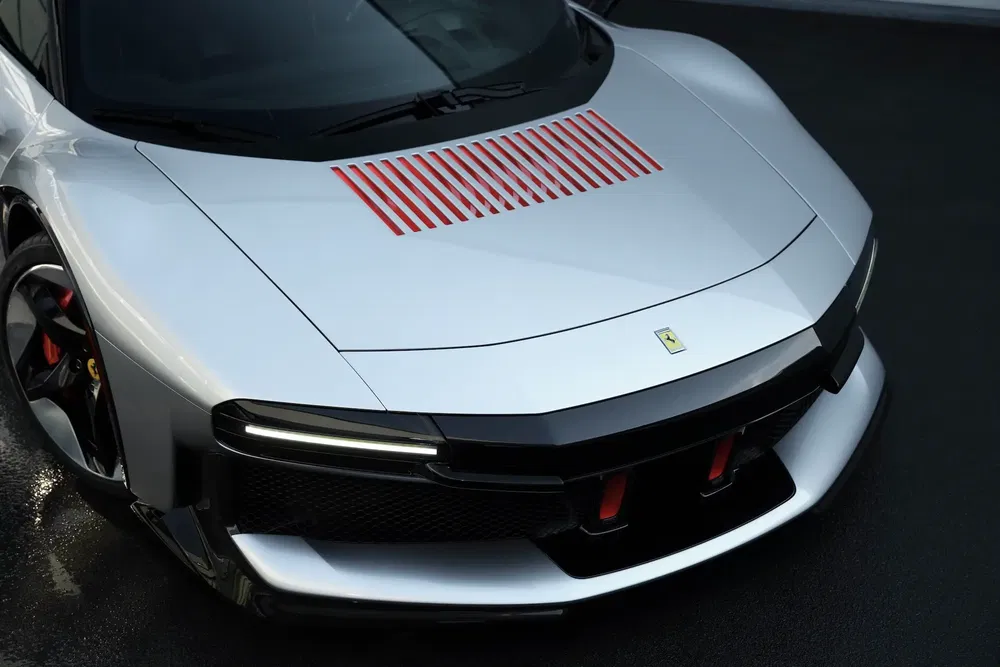 Moderne grijze Ferrari met rode luchtinlaten en aerodynamisch ontwerp.