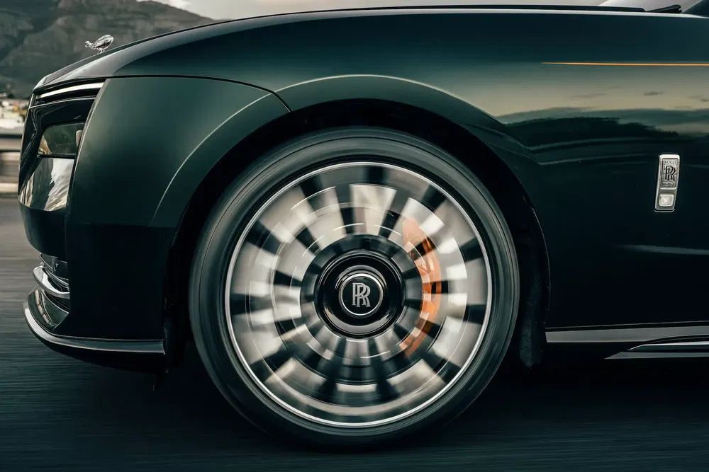 {"fr":"Roue emblématique d'une Rolls-Royce en mouvement avec design luxueux et logo distinctif.","nl":"Iconisch wiel van een Rolls-Royce in beweging met luxe design en kenmerkend logo."}