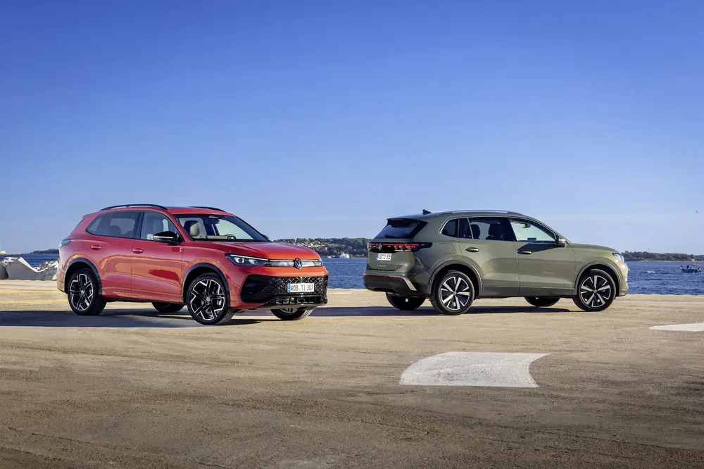 {"fr":"Deux voitures tout-terrain modernes parquées près de la mer sous un ciel bleu clair.","nl":"Twee moderne SUV's geparkeerd bij de zee onder een heldere blauwe lucht."}