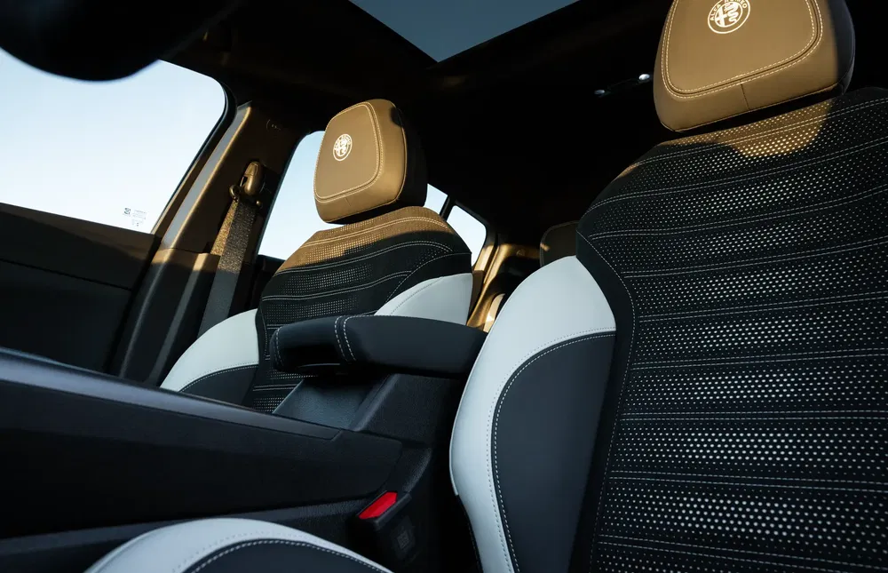 Intérieur moderne d'une Alfa Romeo avec sièges en cuir noir et blanc, appuis-tête logo.