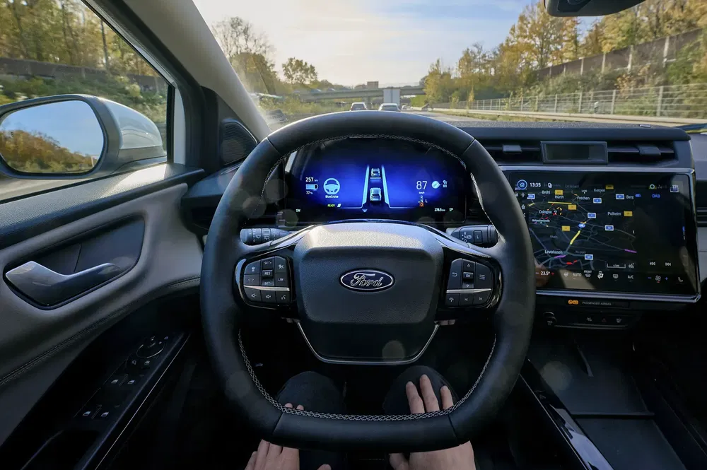 Intérieur d'une voiture Ford avec conduite autonome, affichant le tableau de bord numérique moderne.