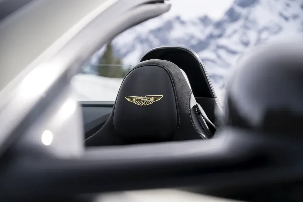 Siège Aston Martin avec logo devant montagnes enneigées, symbolisant luxe et performance.