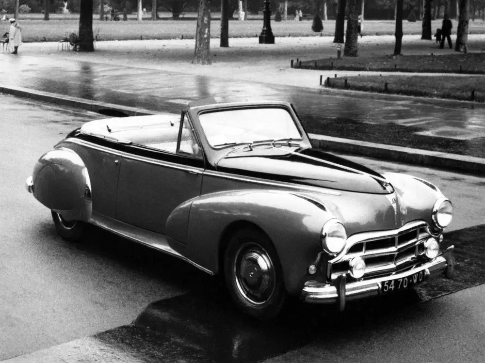 Voiture classique Peugeot 203 Cabriolet noire, garée sur une route humide.
