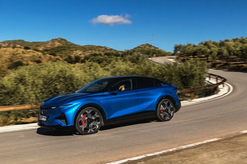 Peugeot 408 bleue sur route sinueuse, paysage montagneux en arrière-plan.