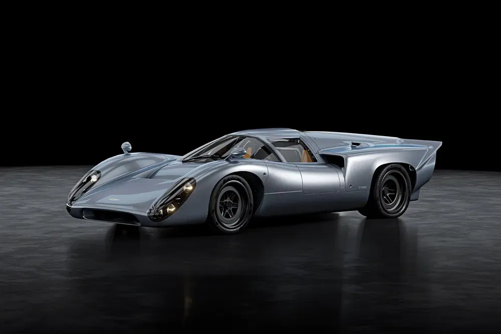 Lola T70 MK3B in metallic grijs, klassieke vormgeving, studioverlichting, zwarte vloer.