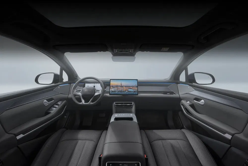 Intérieur moderne d'une voiture électrique, écran tactile central et finitions élégantes.