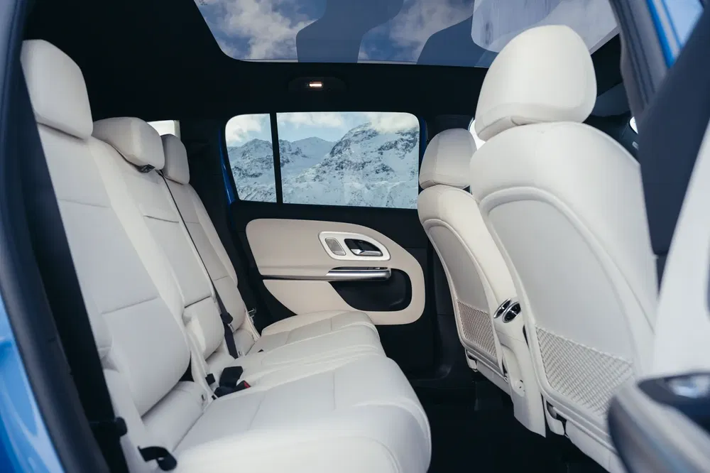 Intérieur spacieux du SUV Mercedes-Benz GLB avec sièges en cuir blanc et toit panoramique.