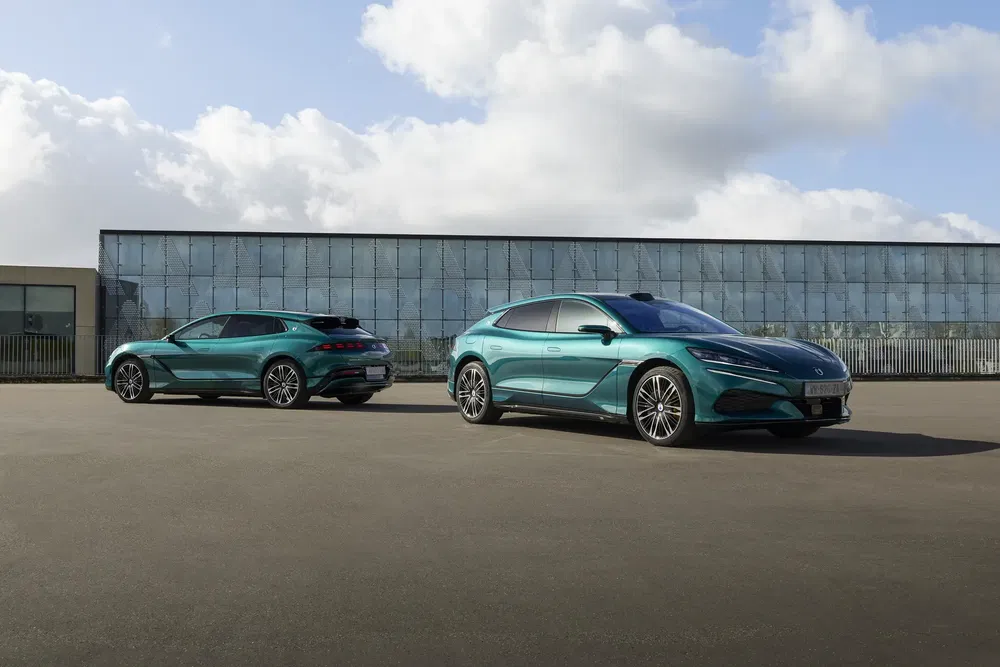 Twee groene elektrische Peugeot 408's geparkeerd voor een modern glazen gebouw.