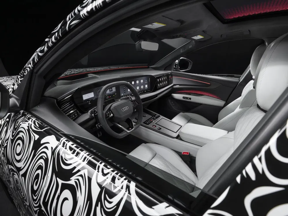 Intérieur d'une Audi avec sièges en cuir blanc et tableau de bord numérique moderne.