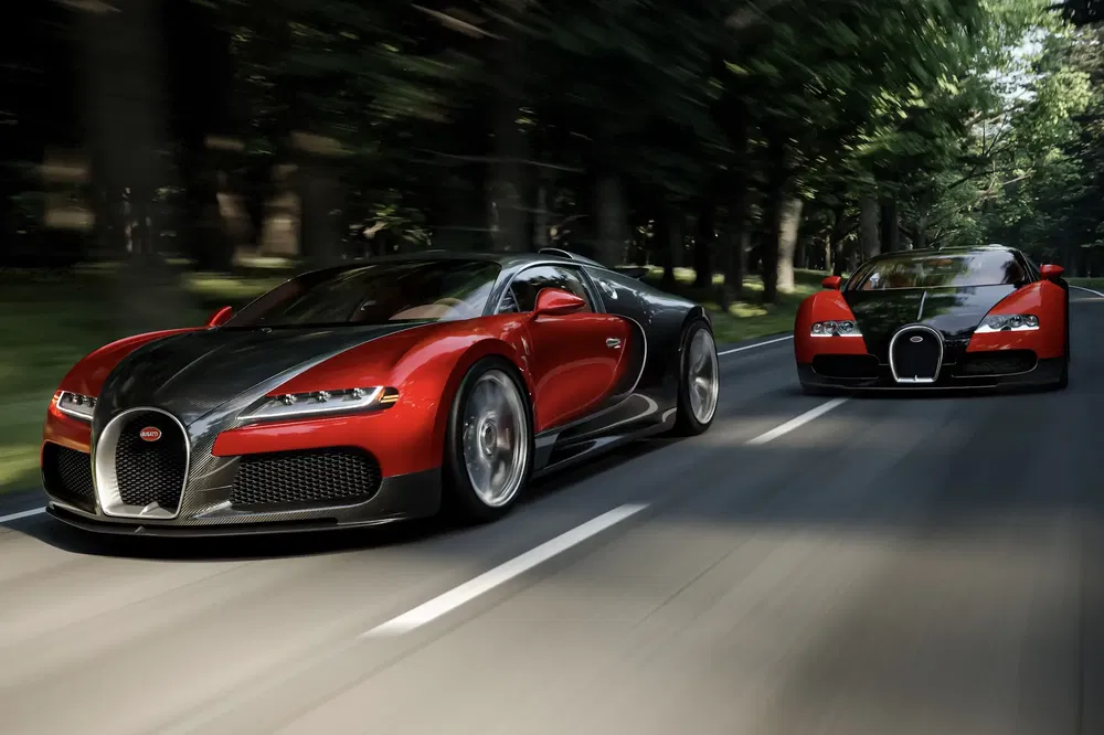 Deux Bugatti Veyron rouges et noires roulant sur une route bordée d'arbres.