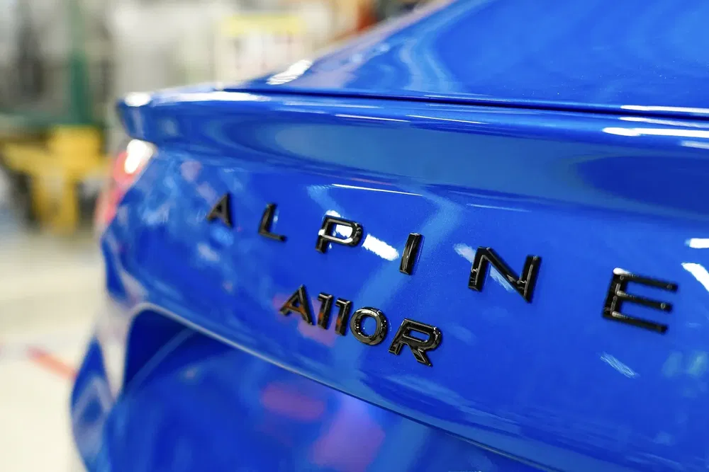 Détail de l'arrière d'une Alpine A110R bleue en gros plan en atelier.