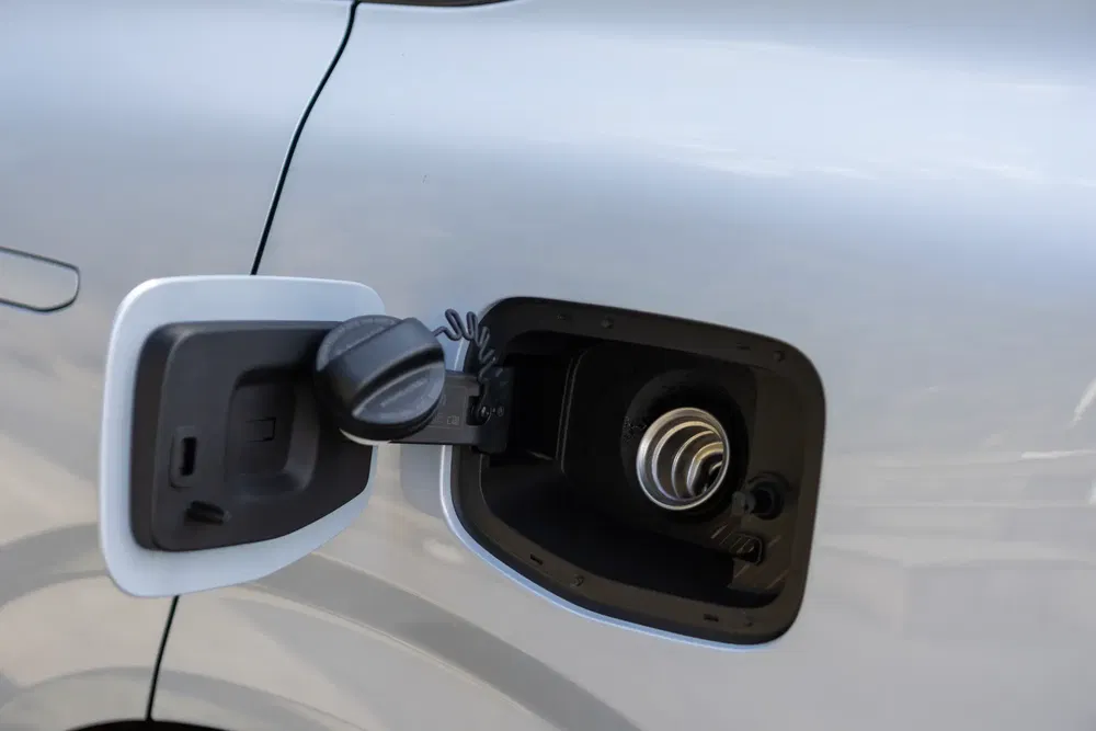 Open brandstofklep van een zilveren auto, met zichtbare tankdop.