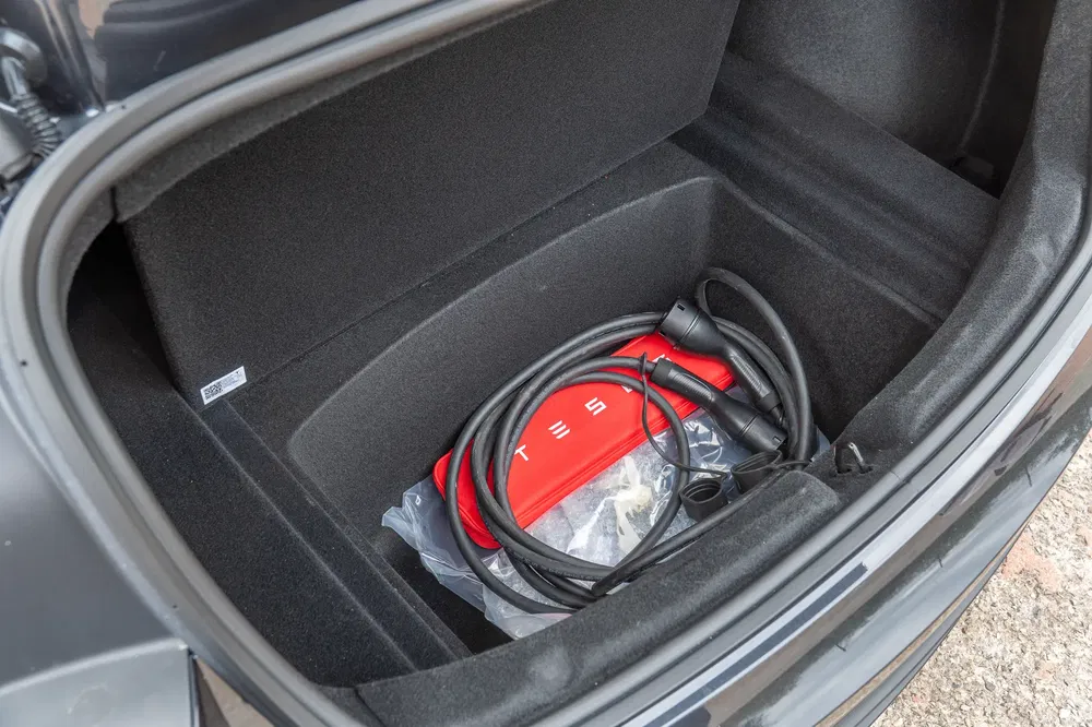 Trunk Tesla avec câble de charge et sac de rangement rouge.