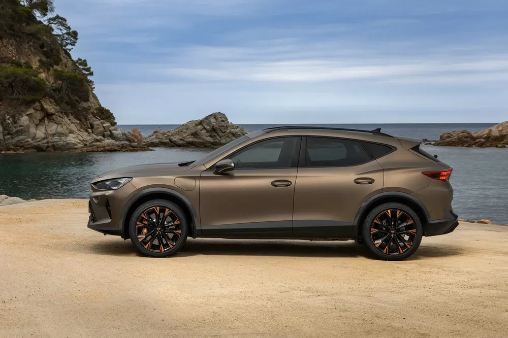 SUV Cupra Formentor marron garé près d'une côte rocheuse sous un ciel bleu.